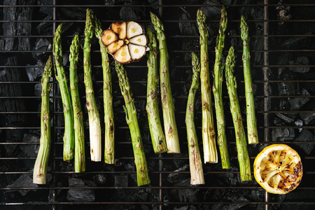 Grilled vegetables green asparagus, garlic, lemon on bbq grill rack over charcoal. Top view, space.の写真素材