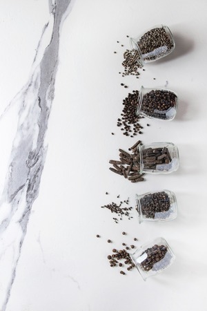 Variety of different black peppers allspice, pimento, long pepper, monks pepper, peppercorns and...
