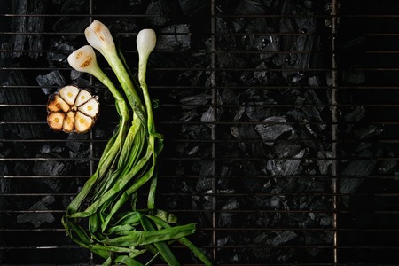 Grilled vegetables spring onion and garlic on bbq grill rack over charcoal. Top view, space. Barbecue conceptの写真素材