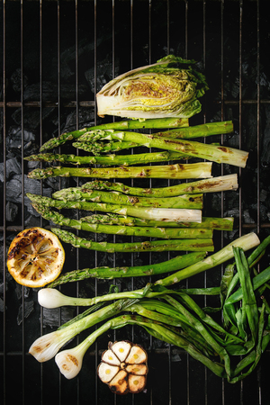 Grilled vegetables green asparagus, garlic, lemon, spring onion, salad on bbq grill rack over charcoal. Top view, space.の写真素材
