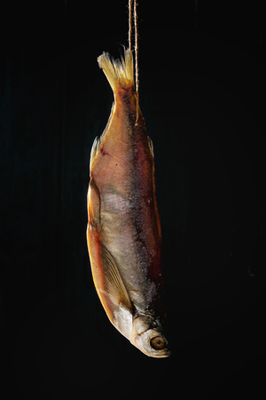 Dried fish or stockfish on thread over dark wooden backgroundの写真素材