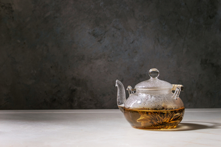 Hot green tea in transparent glass teapot standing on white marble table.の写真素材