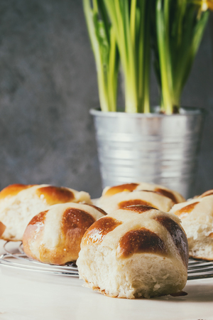 Homemade Easter traditional hot cross buns on cooling rack on white marble table with narcissus flowers.の写真素材