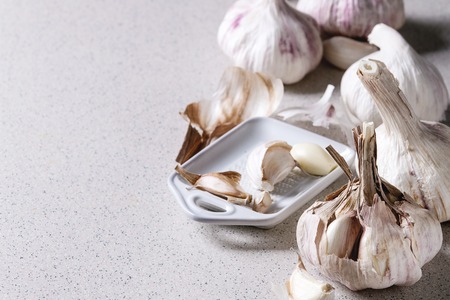 Group of fresh organic garlic bulbs clove whole and peeled with ceramic grater over grey spotted background. Close upの写真素材