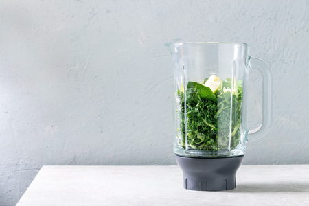 Ingredients for green spinach kale apple smoothie in glass blender on white marble table. Healthy organic eating.の写真素材
