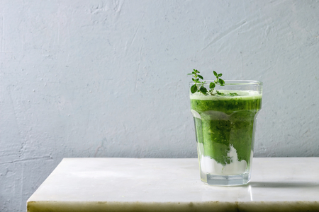 Green spinach kale apple smoothie with yogurt and thyme in glass on white marble table. Healthy organic eating.の写真素材