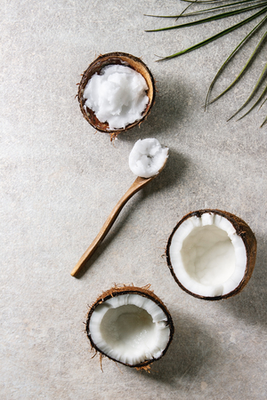 Organic vegan cold pressed coconut oil in coconut shell and wooden spoon over grey texture background. Healthy eating. Flat lay, copy spaceの写真素材