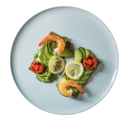 Isolate Vegetarian sandwich with sliced avocado, sun dried tomatoes, shrimps, lemon served on ceramic plate over white. Flat lay, space. Square imageの写真素材