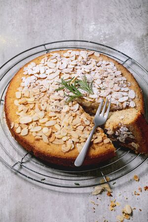 Gluten free almond rosemary homemade cake decorated by almond and sugar powder on cooling rack,...
