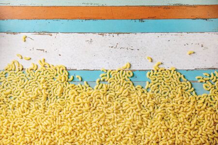 Heap of raw uncooked italian pasta coquillettes over blue wooden plank background. Flat lay, space. Food background.の写真素材