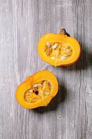 Two halves of raw organic hokkaido pumpkin with seeds over grey wooden background. Flat lay, spaceの写真素材