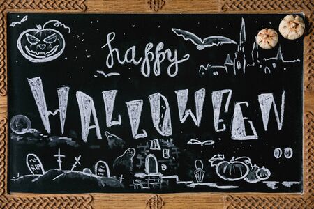 Chalkboard with Happy Halloween hand lettering and drawings of pumpkins, ghosts, cemetery and bats. Autumn Halloween holidays decorations.の写真素材