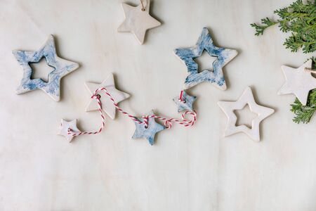 Christmas decoration ceramic stars white and blue glazed, different size, green branches over white...