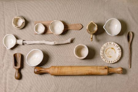Variety of empty different handmade wooden and ceramic dishes, bowls, jugs, ladle and plates over grey linen cloth as background. Flat lay, space. Kitchen cooking conceptの写真素材