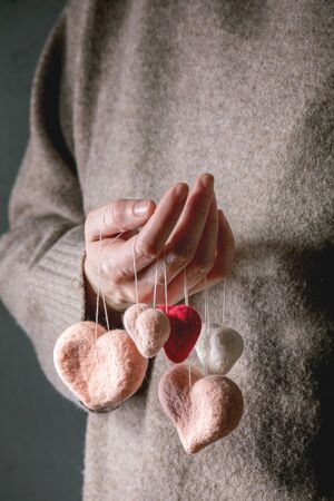 Variety of needle felted hearts on threads in female hands. St Valentines day greeting cardの写真素材
