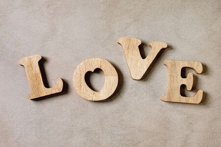 Word LOVE from oak wooden letters over brown texture background. Flat lay, space. St. Valentines...