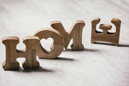 Wooden decorative letters word HOME standing and lying on grey texture table. Concept of love or loss homeの写真素材