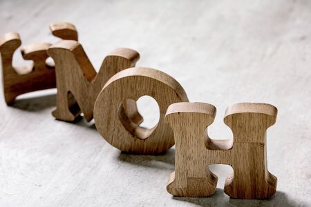 Wooden decorative letters word HOME standing and lying on grey texture table. Concept of love or...