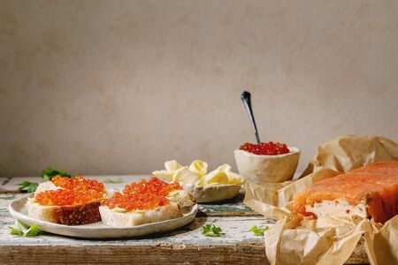 Red salmon caviar in bowl and on wheat bread, homemade salmon pate served with butter on ceramic...