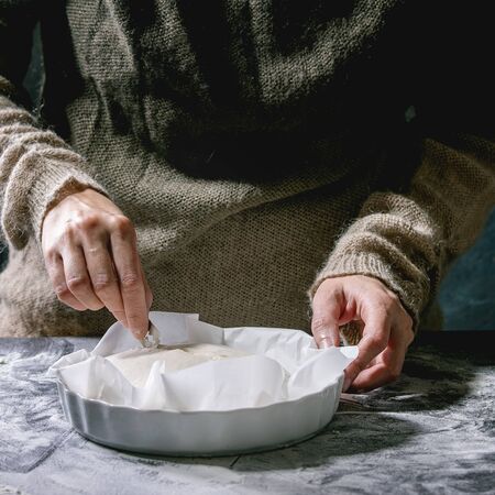 Process of making homemade bread dough. Female hands cuts dough by blade befor baking on dark...