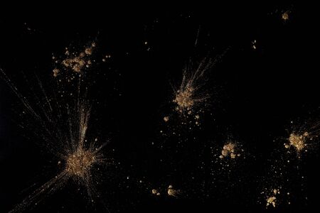Golden powders splash and dust over black. Abstract design background