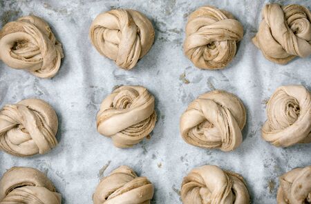 Ready to bake traditional Swedish cardamom sweet buns Kanelbulle on oven tray cover by baking paper....