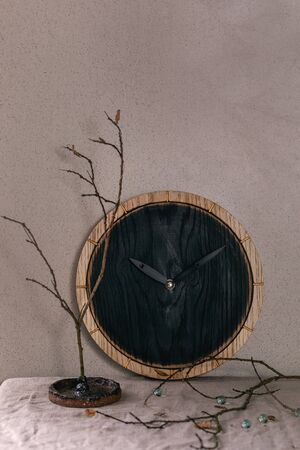 Wall black burned round wooden clocks on table with grey linen tablecloth and dry branches. Interior designの写真素材