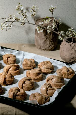 Ready to bake traditional Swedish cinnamon sweet buns Kanelbulle on oven tray cover by baking paper...