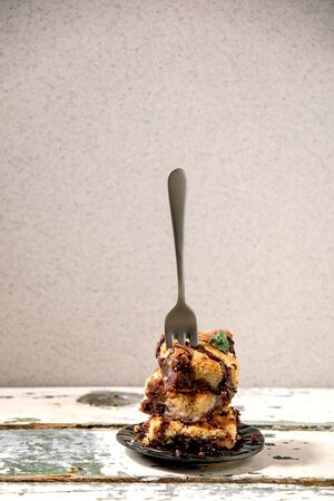 Trend baking Brookies chocolate brownies and cookies homemade cake sliced by squares in stack in ceramic plate with fork on old white wooden table. Copy spaceの写真素材