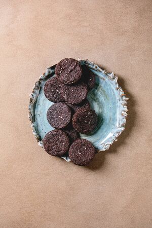 Homemade dark chocolate salted brownies cookies with salt flakes in blue ceramic plate over brown texture background. Flat lay, spaceの写真素材