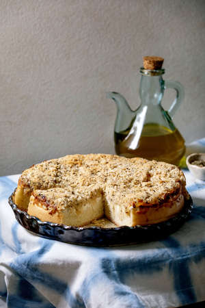 White sicilian focaccia. Traditional baked bread sliced cake with onion, herbs and cheese in ceramic dish served with olive oil on blue and white tablecloth.の写真素材