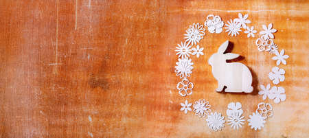 Easter banner with bunny rabbit with different paper flowers around over orange stone background. Flat lay, copy space. Easter holiday greeting card conceptの写真素材