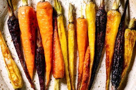 Grilled different colored carrots on ceramic plate. Top view, flat lay. Close up. Vegan dinnerの写真素材