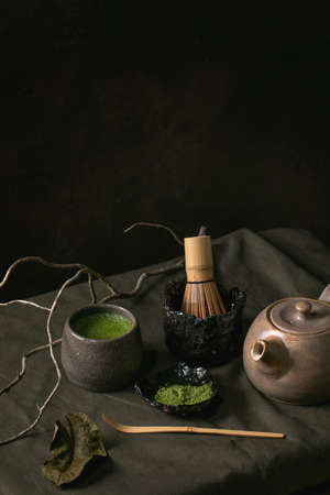 Traditional japanese hot green frothy tea matcha in ceramic cup, powdered matcha, teapot and bamboo...