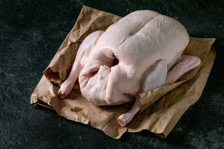 Raw organic uncooked young whole duck on crumpled paper over black texture background. Close-upの写真素材