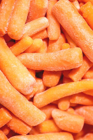Heap of frozen peeled raw organic baby carrot. Food background, macro, close-up. Top view