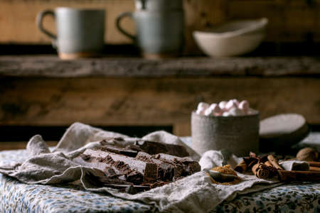 Ingredients for make hot chocolate. Chopped dark chocolate, species, cane sugar, marshmallows on rustic linen tablecloth in country kitchen. Cozy winter drinkの写真素材
