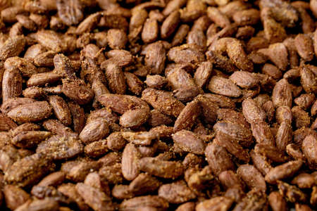 Close up of homemade sweet glazed honey and cane sugar roasted almond nuts on backing paper. Sweet vegan snack. Food backgroundの写真素材