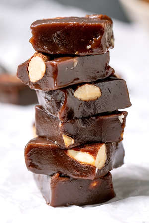 Stack of homemade toffee salted caramel chocolate almond nuts candy on crumpled paper over white...