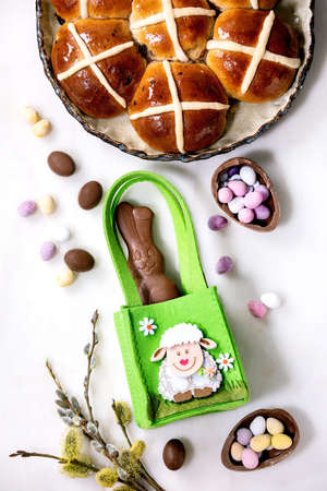 Easter greeting card with chocolate sweets rabbit in green bag, hot cross buns, candies and eggs,...
