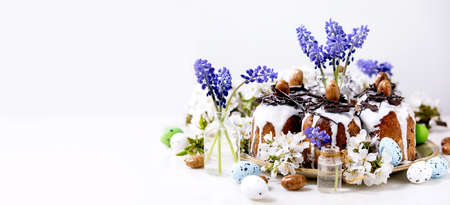 Homemade traditionla Easter kulich cake with chocolate nests and eggs, blossoming cherry branches...