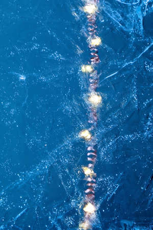 Christmas New Year abstract creative background with garland line lights in transparent blue ice...