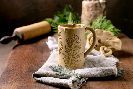 Decorating ceramics. Raw clay mug with a branch imprint. Children's creativity. Amateur ceramics....