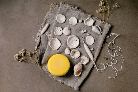 Ceramic workshop idea: handcrafted beads from clay or porcelain. Flat beads of raw white porcelain,...