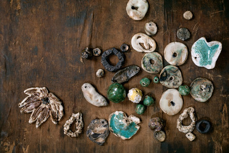 Various handmade ceramic beads. Hobby, jewelry assembly, DIY jewelry. Workshop idea. Dark wooden background, top view, copy spaceの写真素材