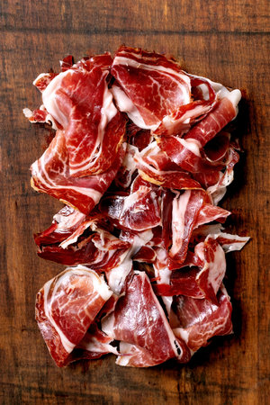 Thinly sliced Spanish ham Jamon Iberico paleta on wooden cutting board. Top view, close upの写真素材