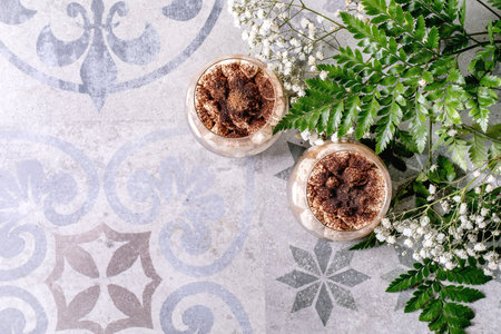 Classic Italian tiramisu in two glasses. Layers of sponge cake and mascarpone cream with cocoa...