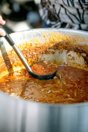 European street food festival. Large pot traditional tomato soup displayed counter with ladle...