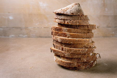 Stack of sliced rye bread with crunchy crust on beige background. Homemade artisan bread perfect for sandwiches breakfast or healthy eating.の写真素材