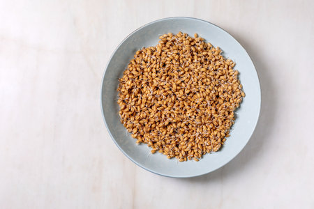 Top view of sprouted wheat grains in blue ceramic plate on white wooden table. Healthy organic vegan ingredient for cooking baking.の写真素材
